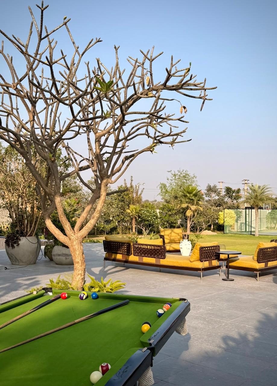 The outdoor billiards table on the terrace at SAHN, beneath the frangipani, with the lawn and court beyond