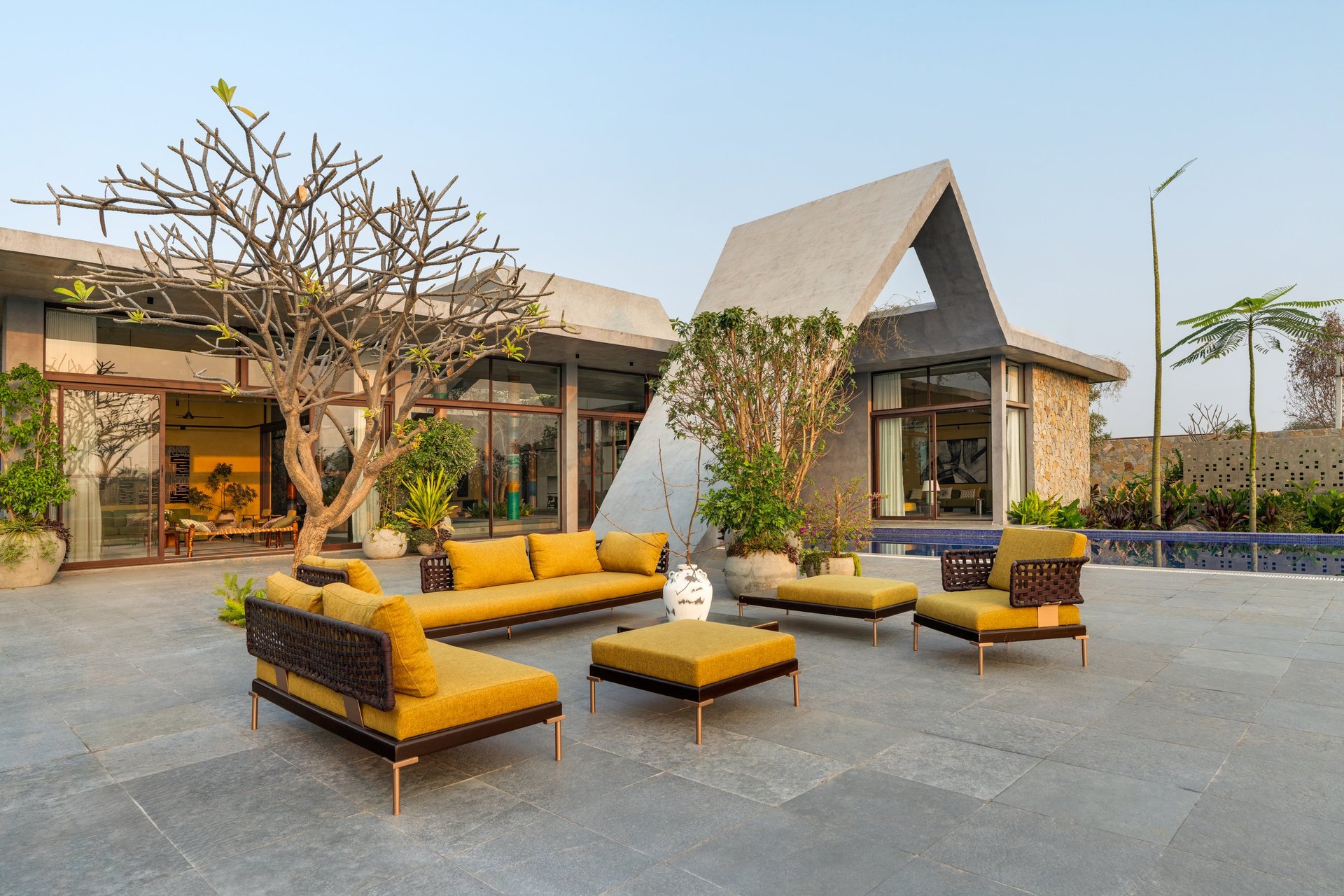 The terrace at SAHN in late light — the house, the frangipani and the outdoor seating